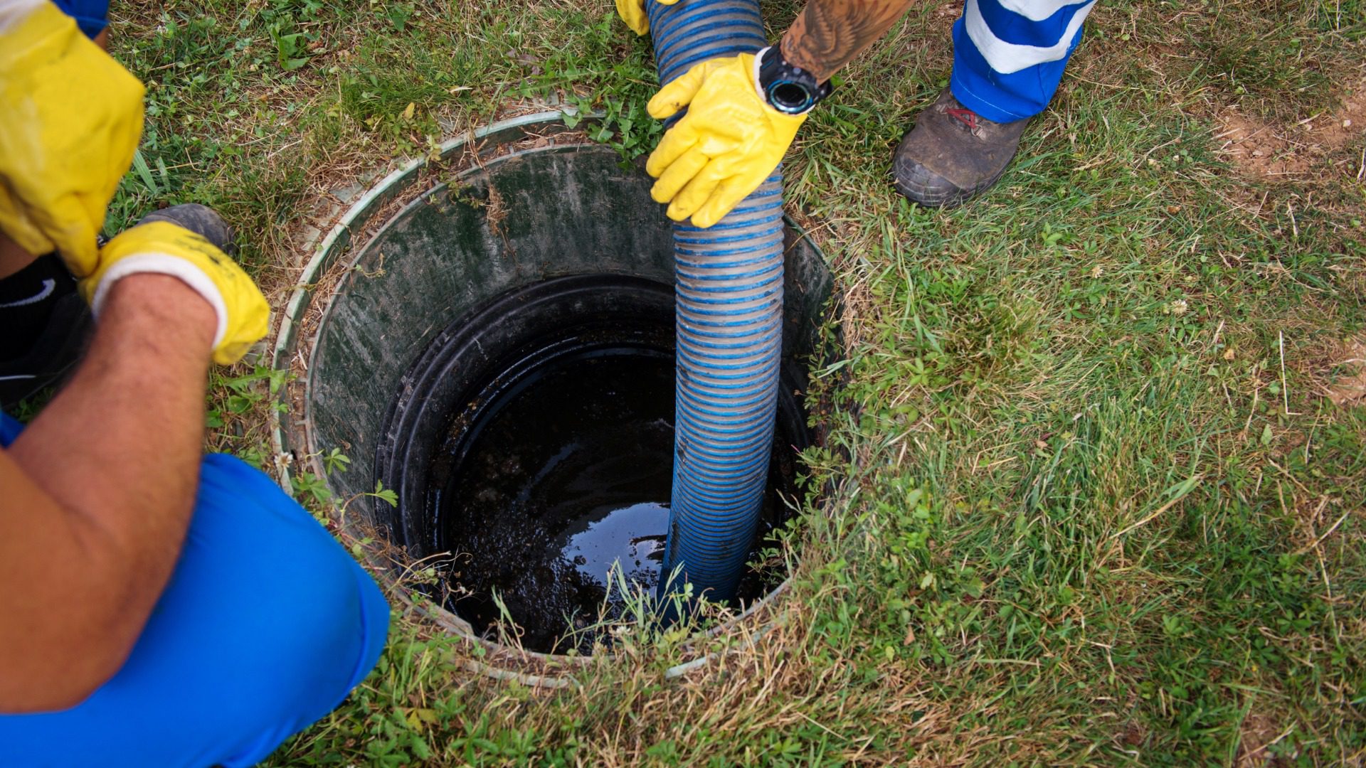 Close-up of a man's hands in yellow gloves and blue gloves installing a sewer pipe.